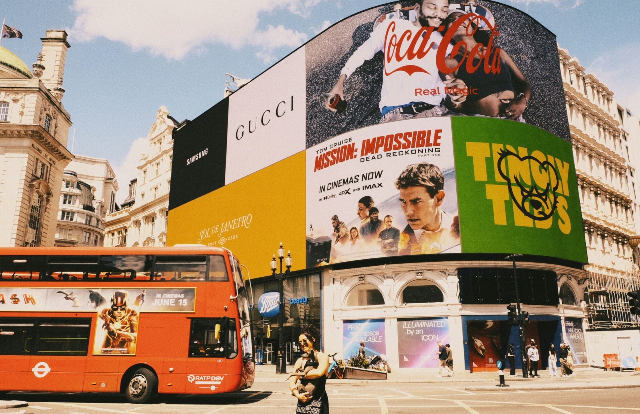 Piccadilly Circus London with Coca-Cola billboard, Mission: Impossible movie ad, red double-decker bus, people walking